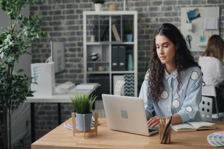 A woman sitting while looking at her laptop